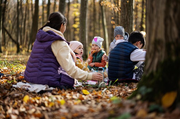 Mãe com filhos no piquenique em família na floresta de outono