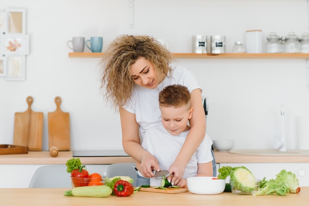 Mãe com filhos preparando salada de legumes em casa