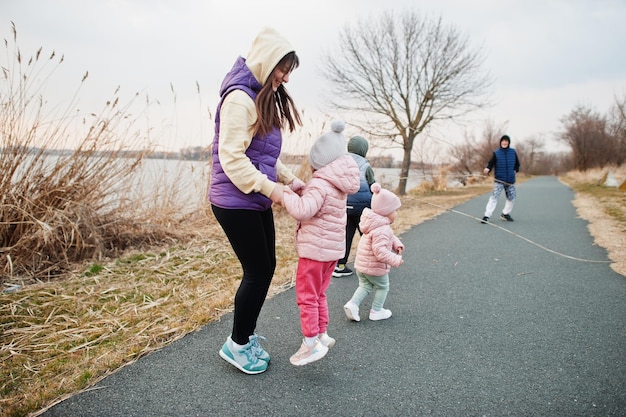 Mãe com filhos pulando e se divertindo no caminho à beira do lago