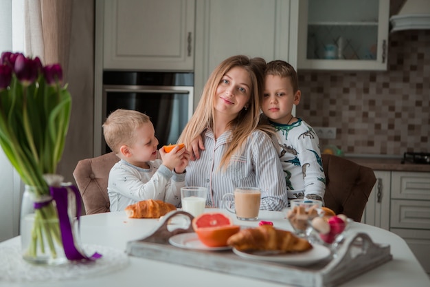 Mãe com filhos tomando café na cozinha