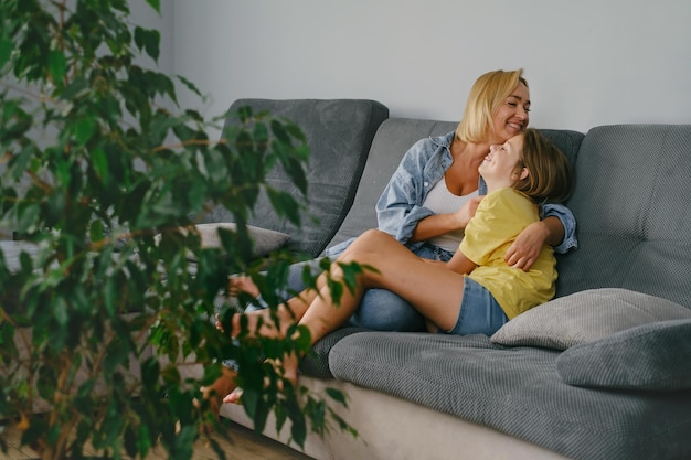 Mãe com menina adolescente abraçada no sofá