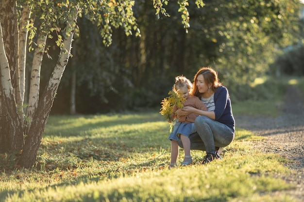 Mãe com menina criança no parque ao pôr do sol à noite ensolarada Infância feliz Countyside