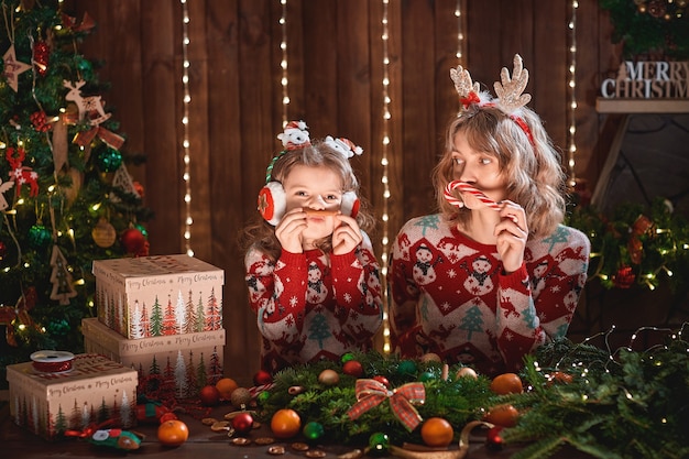 Mãe com menina criança perto de árvore de natal.