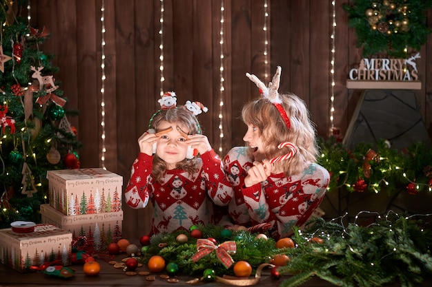 Mãe com menina criança perto de árvore de Natal.