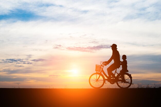 Mãe com seu filho andando de bicicleta ao pôr do sol