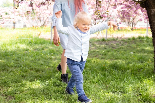 Mãe com seu filho brincando na primavera perto da cerejeira japonesa sakura conhece a primavera Sakura muito lindamente floresce com flores cor de rosa