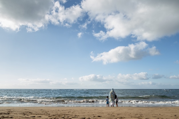 Mãe com seu filho e filha, olhando para o mar na praia de las canteras em Gran Canaria, Ilhas Canárias, Espanha