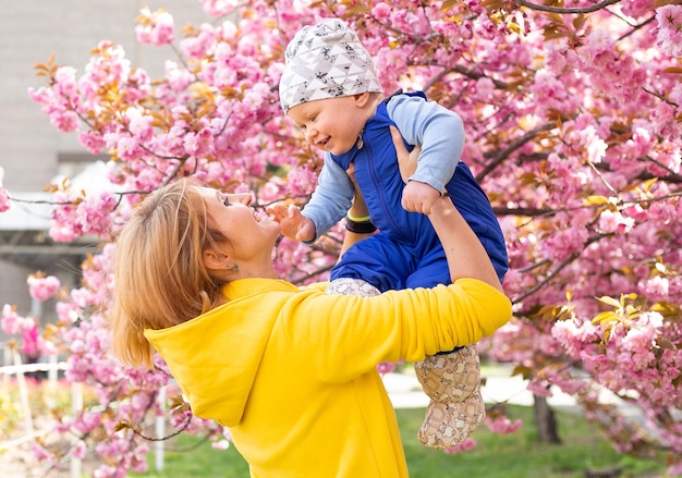 Mãe com seu filho na primavera perto da cerejeira japonesa sakura conhece a primavera Sakura muito lindamente floresce com flores cor de rosa