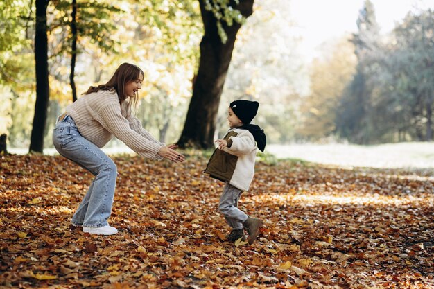 Mãe com seu filho pequeno caminhando no parque outonal