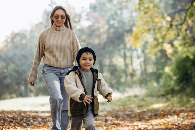 Mãe com seu filho pequeno caminhando no parque outonal