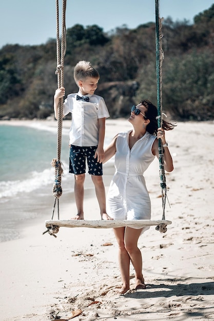 Mãe com seu filho se divertindo balançando na praia tropical. Phuket. Tailândia. Conceito de férias em família