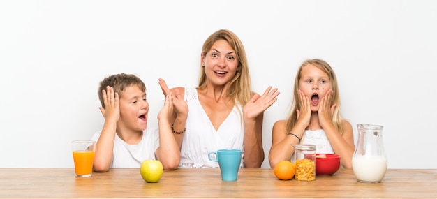 Mãe com seus dois filhos tomando café da manhã