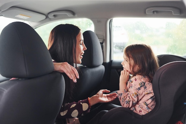 Mãe com sua filha dentro do automóvel moderno juntos