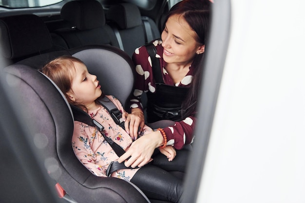 Foto mãe com sua filha dentro do automóvel moderno juntos