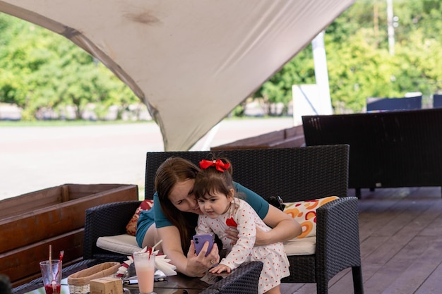 mãe com sua filha desfrutando em um café ao ar livre