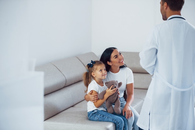 Mãe com sua filha está visitando a clínica. Ouvindo o médico.