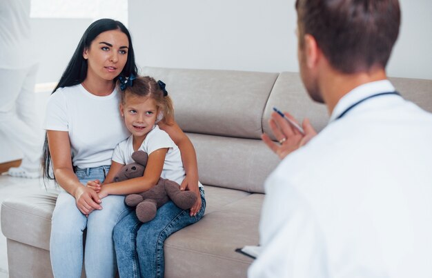 Mãe com sua filha está visitando a clínica. Ouvindo o médico.