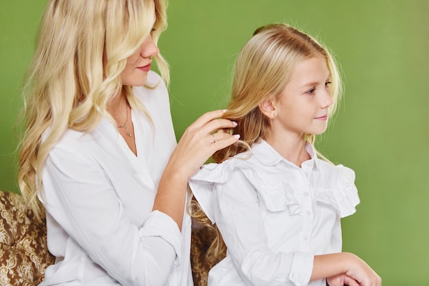 Mãe com sua filha junto no estúdio com fundo verde.