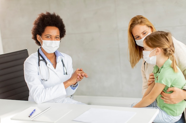 Foto mãe com sua filha no exame do pediatra pela médica afro-americana