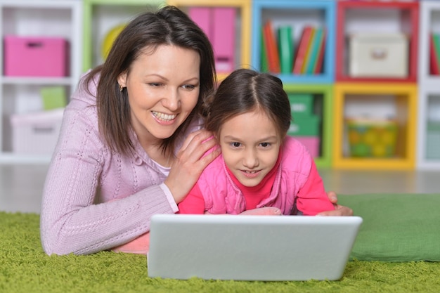 Mãe com sua filha usando laptop