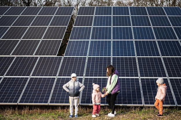 Mãe com três filhos no fundo de energia ecológica de painéis solares