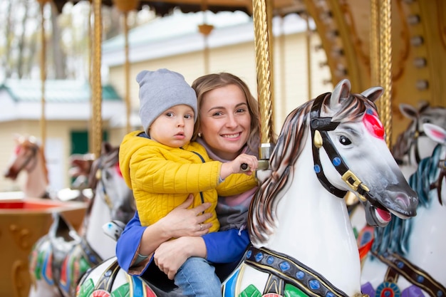 Mãe com um bebê alegre em um carrosselAmor de mãe