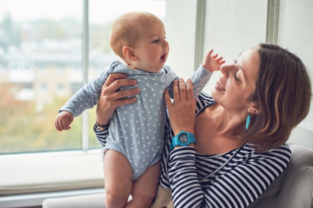 Mãe com um bebê de 8 meses sentado em um sofá em casa