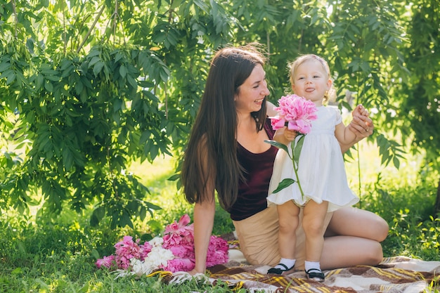 Mãe com um bebê nos braços em um dia ensolarado caminha pelo parque.