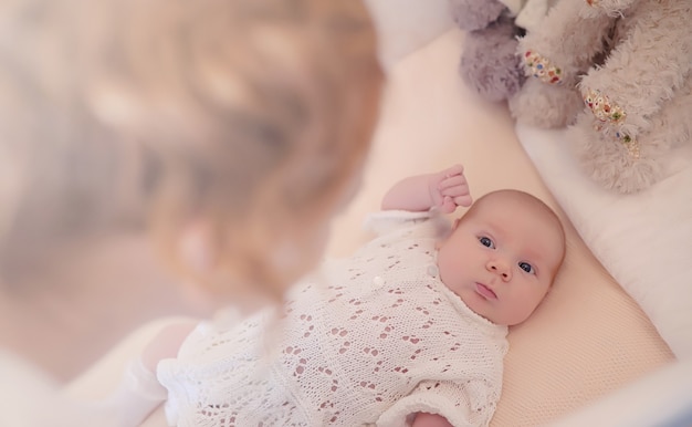 Mãe com um bebê recém-nascido nos braços. a garota está segurando um bebê na frente da janela. recém-nascido nas mãos da mãe.