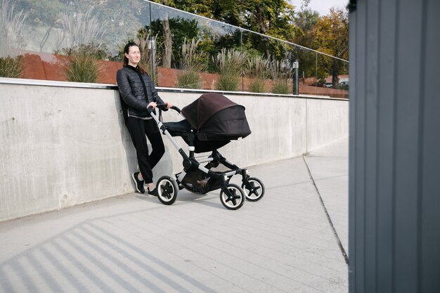 Mãe com um carrinho de bebê ou carrinho nas ruas da cidade moderna