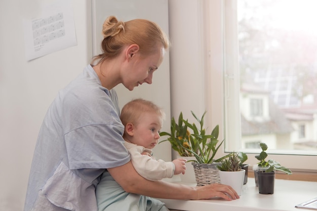 Mãe com uma criança explorando plantas de casa mãe bonita com bebê pequeno perto de plantas de casa