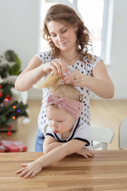 Mãe consertando o aparelho auditivo de implante coclear de sua filha na árvore de natal conceito de surdez e diversidade Tecnologias inovadoras i