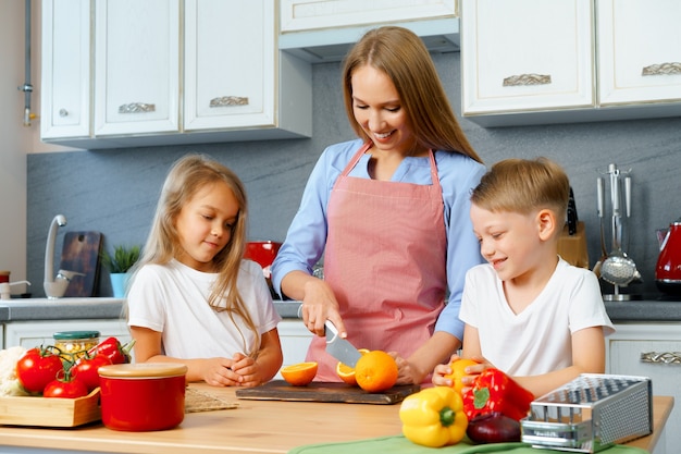 Mãe cozinhando com seus filhos na cozinha