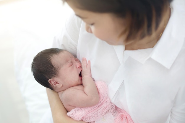 Mãe cuida de seu adorável bebê recém-nascido chorando com cuidado