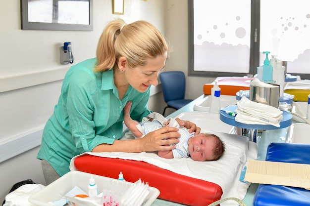 Mãe cuida de seu bebê recém-nascido na maternidade. Primeiro banho.