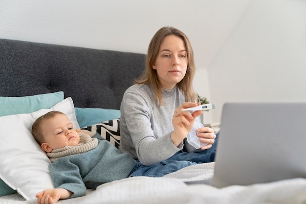 Mãe cuidando de seu filho e teleconsultoria com médico