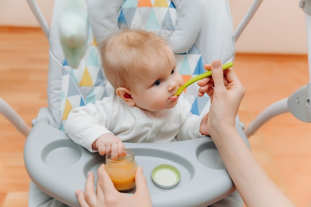 Mãe dá molho de frutas para bebêmãe alimenta bebê com comida de bebê