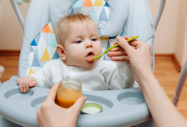 Mãe dá molho de frutas para bebêmãe alimenta bebê com comida de bebê