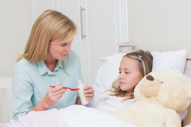 Mãe dando a sua filha tosse medicamento