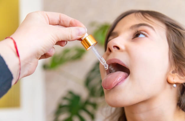 Mãe dando gotas de vitamina com conta-gotas para o filho. suplementos dietéticos para crianças. Foco seletivo.