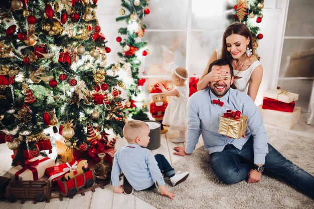 Mãe dando presente para o marido na árvore de natal