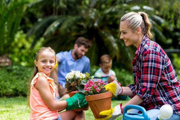 Mãe dando vaso de flores para a filha sorridente no quintal