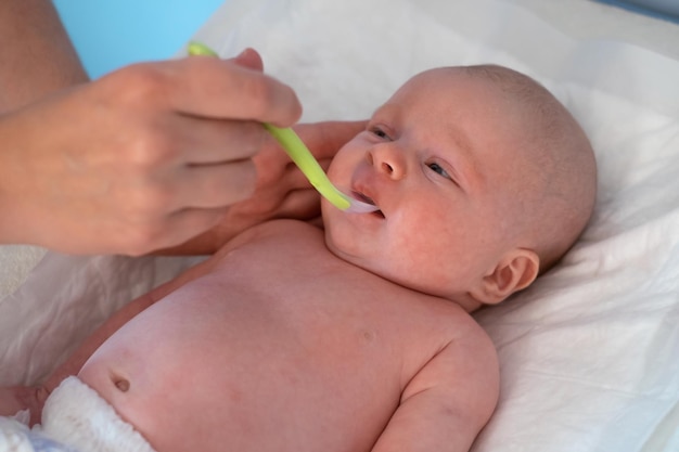 Mãe dando vitaminas ao bebê com colher.