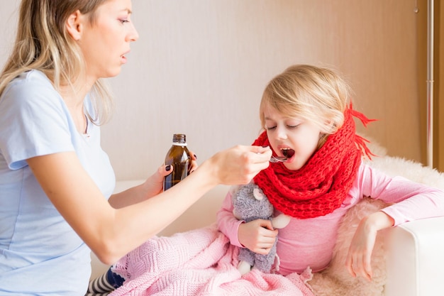 Mãe dando xarope para sua filha doente
