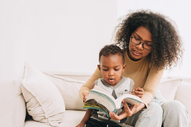 Mãe de educação dando aprendizado para menino interessante para ler o livro para criança inteligente família de negros africanos