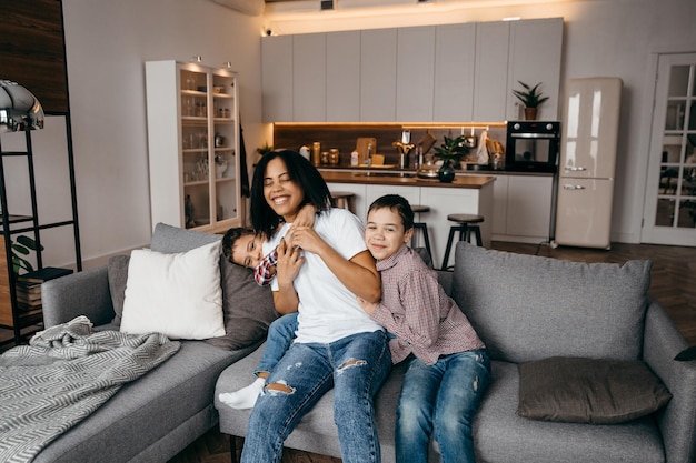 Mãe de família afro-americana feliz e dois filhos brincando e se divertindo em casa juntos