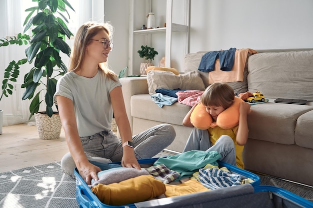 Mãe de família e filho fazendo uma mala e um travesseiro de viagem juntos em uma viagem ou férias