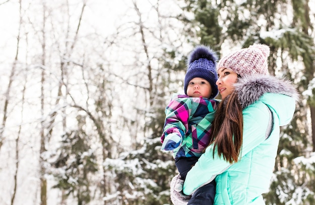 Mãe de família feliz e filha bebê criança em um inverno caminhar na floresta