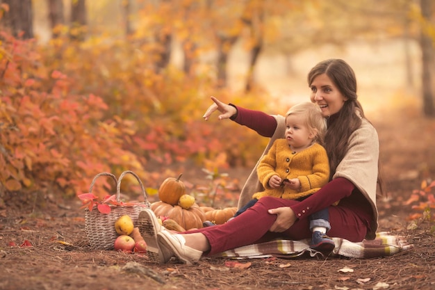 Mãe de família feliz e filha brincando no parque natural de outono no pôr do sol