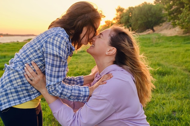 Mãe de família feliz e filha criança no parque natural no verão na grama verde